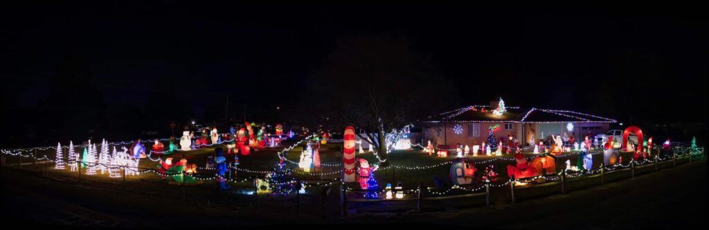 A picture of a home taken at night with christmas lights and decorations filling the yard